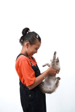 Küçük Asyalı bir kız kedi yavrusunu sevgiyle kucaklıyor. Sevimli. Beyaz arka planda izole edilmiş. Uluslararası kedi günü fotoğraf konsepti.