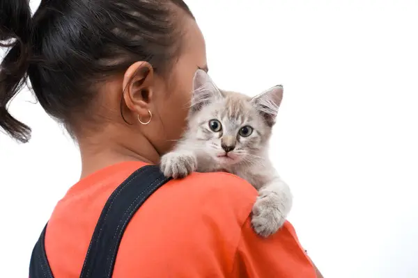 Küçük Asyalı bir kız kedi yavrusunu sevgiyle kucaklıyor. Sevimli. Beyaz arka planda izole edilmiş. Uluslararası kedi günü fotoğraf konsepti.