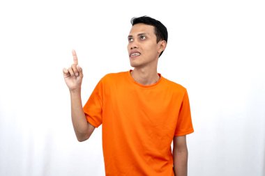 Portakal rengi tişört giyen genç bir Asyalı 'nın portresi promosyon alanı için fotokopi alanını işaret ediyor. beyaz arkaplanda izole.