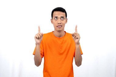 Portakal rengi tişört giyen genç bir Asyalı 'nın portresi promosyon alanı için fotokopi alanını işaret ediyor. beyaz arkaplanda izole.