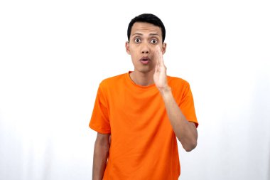 Elleri ağzının kenarında turuncu tişört giyen genç Asyalı bir adamın portresi. Dedikoduları fısıldıyor ve sırlarını anlatıyor. Beyaz arka planda izole edilmiş haberleri paylaşıyorlar..