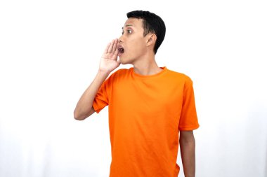 Elleri ağzının kenarında turuncu tişört giyen genç Asyalı bir adamın portresi. Dedikoduları fısıldıyor ve sırlarını anlatıyor. Beyaz arka planda izole edilmiş haberleri paylaşıyorlar..