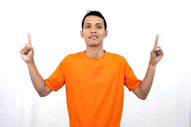 Portakal rengi tişört giyen genç bir Asyalı 'nın portresi promosyon alanı için fotokopi alanını işaret ediyor. beyaz arkaplanda izole.