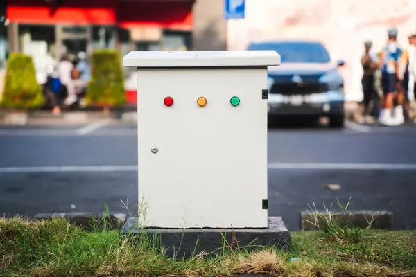 stock image medium sized electrical panel box located outdoors, in a parking lot or garden.