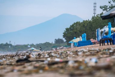 Bali, Endonezya - 09 Mart 2024: Kuta Beach Bali 'nin sabah manzarası. Arka planda Batukaru Dağı ile birlikte bir sürü çöp yığını var. Kirlilik teması