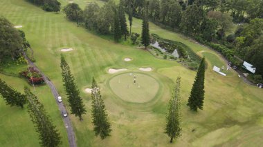 Hava manzaralı, yeşil ve düzgün düzenlenmiş golf sahası, dağlık bir bölgede..