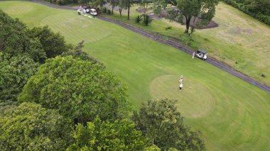 Hava manzaralı, yeşil ve düzgün düzenlenmiş golf sahası, dağlık bir bölgede..