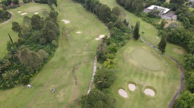 Hava manzaralı, yeşil ve düzgün düzenlenmiş golf sahası, dağlık bir bölgede..