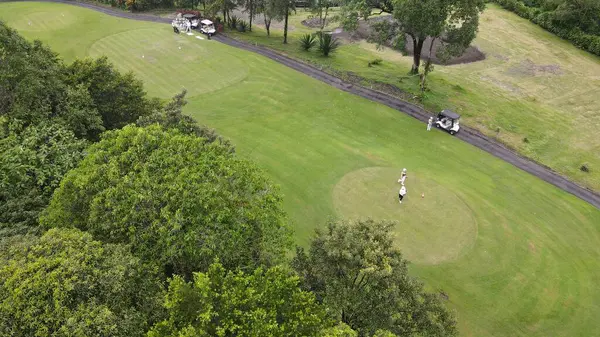 Hava manzaralı, yeşil ve düzgün düzenlenmiş golf sahası, dağlık bir bölgede..