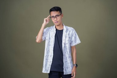 Gözlüklü genç Asyalı bir adam, aklına bir fikir geliyor. Ordu yeşil arka planında izole edilmiş..