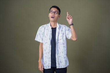 Gözlüklü genç Asyalı bir adam, aklına bir fikir geliyor. Ordu yeşil arka planında izole edilmiş..