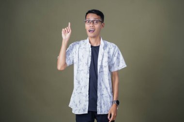 Gözlüklü genç Asyalı bir adam, aklına bir fikir geliyor. Ordu yeşil arka planında izole edilmiş..