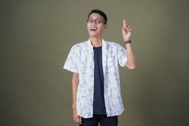 Gözlüklü genç Asyalı bir adam, aklına bir fikir geliyor. Ordu yeşil arka planında izole edilmiş..