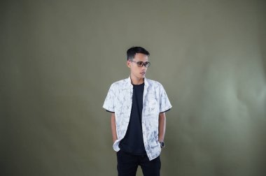 Gözlüklü genç Asyalı adam dik duruyor, yasak, iyi değil. Ordu yeşil arka planında izole edilmiş..