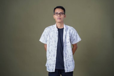 Gözlüklü genç Asyalı adam dik duruyor, yasak, iyi değil. Ordu yeşil arka planında izole edilmiş..