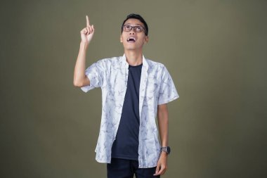 Gözlüklü genç Asyalı bir adam, aklına bir fikir geliyor. Ordu yeşil arka planında izole edilmiş..