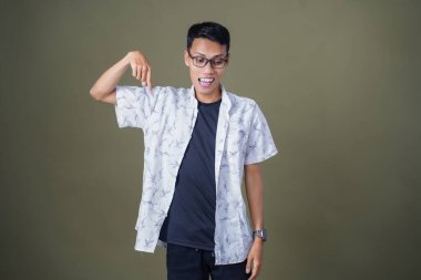 Boş reklam alanını gösteren gözlüklü genç bir Asyalı. Ordu yeşil arka planında izole edilmiş..