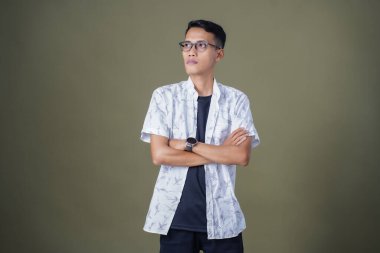 Gözlüklü Asyalı genç adam kollarını kavuşturmuş, yasak, iyi değil. Ordu yeşil arka planında izole edilmiş..