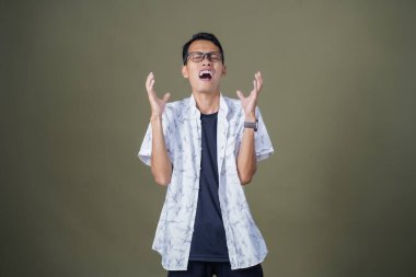 Gözlüklü, beyaz gömlekli, Asyalı bir adam. Baş döndürücü, sorunlu, üzgün bir ifade. Ordu yeşil arka planında izole edilmiş..