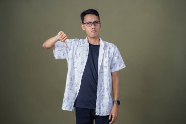 Gözlüklü genç Asyalı hayır, yasak, iyi bir jest yapmıyor. Ordu yeşil arka planında izole edilmiş..