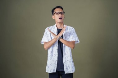 Gözlüklü genç Asyalı hayır, yasak, iyi bir jest yapmıyor. Ordu yeşil arka planında izole edilmiş..