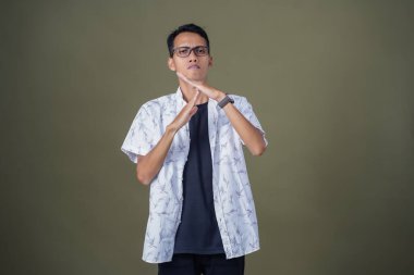 Gözlüklü genç Asyalı hayır, yasak, iyi bir jest yapmıyor. Ordu yeşil arka planında izole edilmiş..