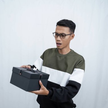 Gözlüklü Asyalı genç bir adam süveter giyiyor ve sürpriz bir hediye alıyor. Beyaz bir arkaplanda izole edilmiş.