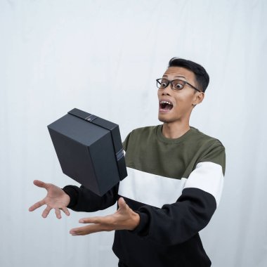 Gözlüklü Asyalı genç bir adam süveter giyiyor ve sürpriz bir hediye alıyor. Beyaz bir arkaplanda izole edilmiş.