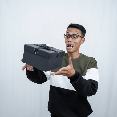 Gözlüklü Asyalı genç bir adam süveter giyiyor ve sürpriz bir hediye alıyor. Beyaz bir arkaplanda izole edilmiş.