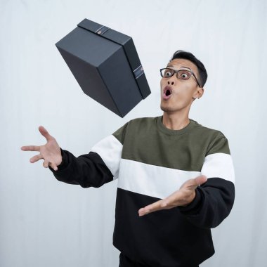 Gözlüklü Asyalı genç bir adam süveter giyiyor ve sürpriz bir hediye alıyor. Beyaz bir arkaplanda izole edilmiş.