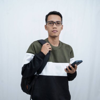 Akıllı telefon tutan gözlüklü, süveter giyen Asyalı genç bir adam. Beyaz arkaplanda izole.