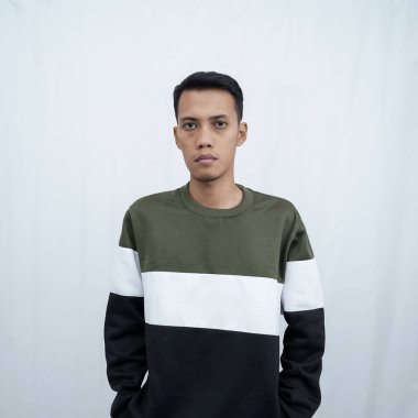 Gözlüklü, süveter giyen genç bir Asyalı düzgün, havalı, gülümseyen bir poz veriyor. Beyaz arkaplanda izole.