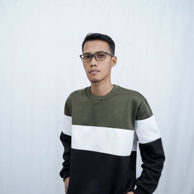 Gözlüklü, süveter giyen genç bir Asyalı düzgün, havalı, gülümseyen bir poz veriyor. Beyaz arkaplanda izole.