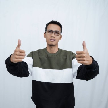 Gözlüklü, süveter giyen, gülümseyen ve işaret veren Asyalı genç bir adam. Beyaz arkaplanda izole.