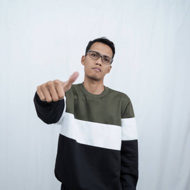 Gözlüklü, süveter giyen, gülümseyen ve işaret veren Asyalı genç bir adam. Beyaz arkaplanda izole.