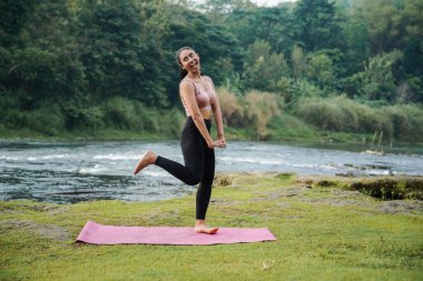 Isınmayı bitirdikten ya da kaslarını esnettikten sonra kahverengi tenli, ince Asyalı bir kızın mutlu ifadesi..