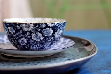 Close up photo of blue porcelain dinnerware on a table. Empty plates and bowls. Decorative blue tableware.