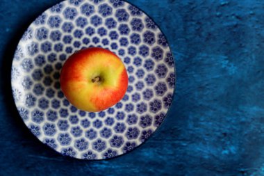 Fruit on a blue decorative crockery. Close up photo of beautifully patterned tableware. Textured backdrop with copy space. 