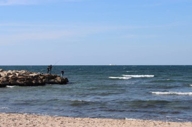 Sunny spring day on a beach. Calm sea water, blue sky, sandy beach. 