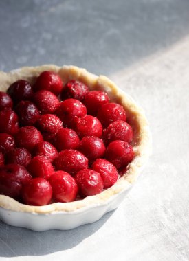 Big juicy cherries on a tart. Sweet pie close up photo. Light grey background with copy space. 