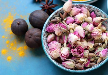 Kurumuş gül tomurcukları yakın plan fotoğraf. Mavi bir seramik kasede gül çiçekleri. Kopyalama alanı olan mavi arkaplan. 