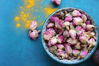 Kurumuş gül tomurcukları yakın plan fotoğraf. Mavi bir seramik kasede gül çiçekleri. Kopyalama alanı olan mavi arkaplan. 