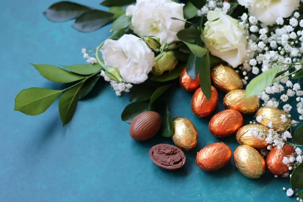 stock image Chocolate Easter eggs close up photo. Holiday sweets on a blue background with copy space. Still life with Gypsophila flowers and wrapped eggs bowl. Easter celebration concept. 