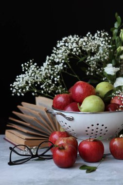 Masanın üzerinde açık bir kitap. Eski bir kitabın sarı sayfalarının fotoğrafını çek. Beyaz çigila çiçekleri ve kitapla basit kompozisyon.. 