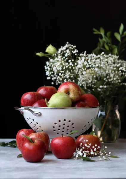 Beyaz metalik kevgire organik armutlar ve elmalar. Sehpadaki mevsimlik meyvelerin fotoğrafını çek. Elmalar ve çingene çiçekleriyle dolu renkli bir hayat. Doğal vitaminler ve antioksidan konsepti. 