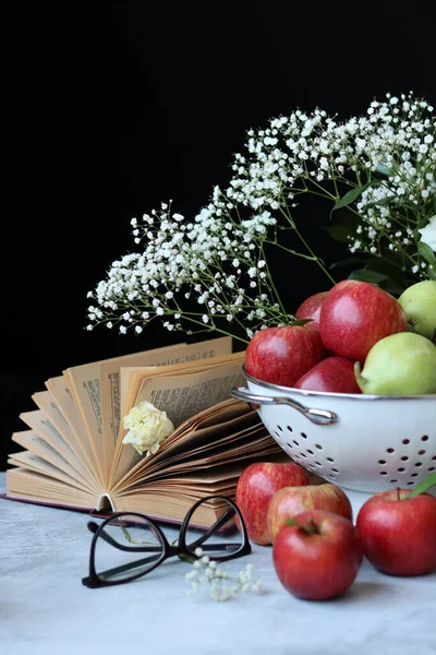 果物はまだ生きてる テーブルの上に赤いリンゴ 開いている本 白いジプシーの花 コピースペースの黒い背景 旬の果物の鮮やかな色 — ストック写真