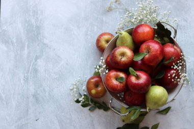 Beyaz kevgirde parlak kırmızı elmalar. Masadaki organik meyvelerin yakın plan fotoğrafını çek. Mevsimlik meyvelerin canlı renkleri. Taze konsept yemek. Kopyalama alanı olan parlak gri arkaplan. 