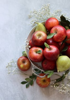 Beyaz kevgirde parlak kırmızı elmalar. Masadaki organik meyvelerin yakın plan fotoğrafını çek. Mevsimlik meyvelerin canlı renkleri. Taze konsept yemek. Kopyalama alanı olan parlak gri arkaplan. 