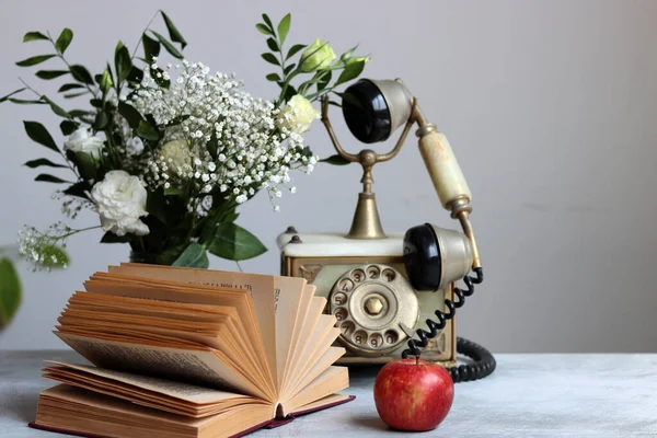 Still life with an old open book on a desk. Retro style photo. Vintage objects on a table.