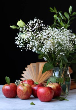 Basit kompozisyon açık kitap, beyaz çiçekler ve kırmızı elmalarla hayat devam ediyor. Eğitim kavramı. 